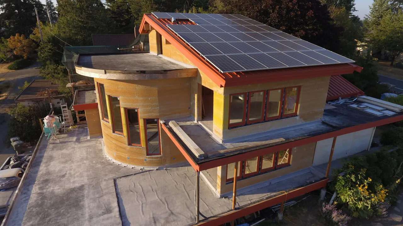 A finished two-storey hempcrete home with solar panels on the roof