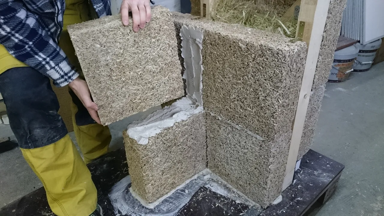 Hands placing a hempcrete block on a wall